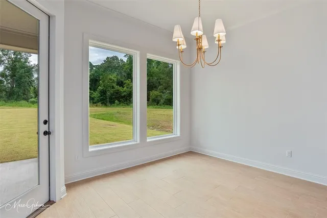 a view of empty room with window wooden floor and chandelier