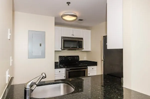 a kitchen with a sink and a stove top oven with granite countertops