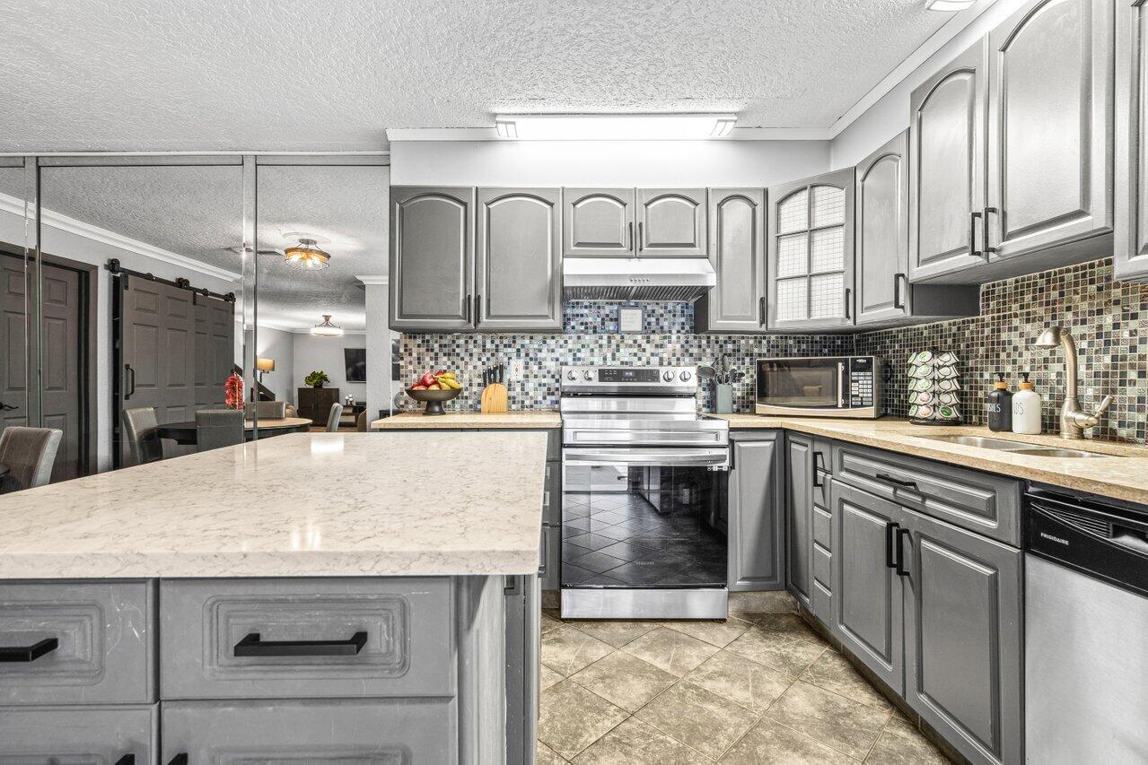 22180 Boca Rancho Drive, Unit B Boca Raton, FL 33428 - Photo 15 of 22 a kitchen with kitchen island granite countertop wooden cabinets and white appliances
