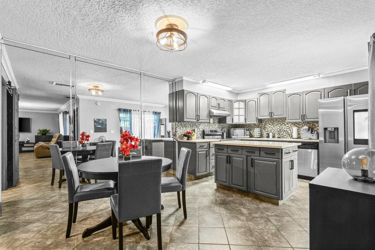 22180 Boca Rancho Drive, Unit B Boca Raton, FL 33428 - Photo 8 of 22 a kitchen with a table chairs microwave and cabinets