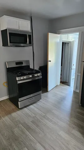 a view of an empty room with wooden floor and a fireplace