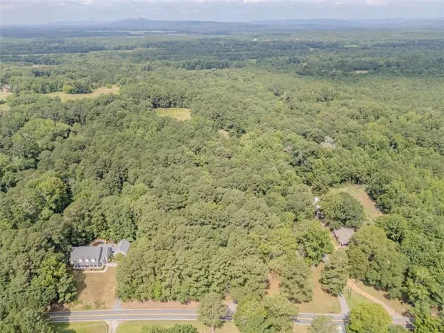 an aerial view of residential house with outdoor space and trees all around