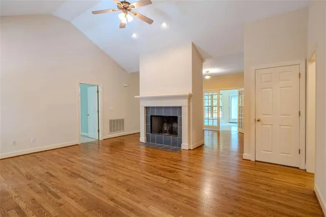 a view of an empty room with wooden floor fireplace and a window