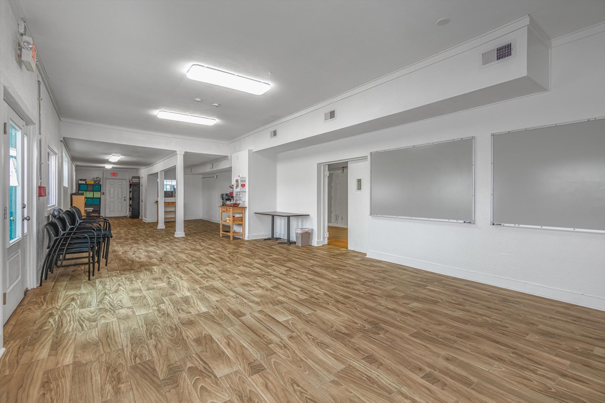 905 43rd Street Galveston, TX 77550 - Photo 10 of 43 This spacious room features vinyl flooring, ample lighting, and white walls with bulletin boards, offering a versatile space ideal for gatherings or a creative workspace.