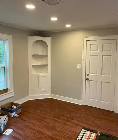 an empty room with wooden floor closet and windows