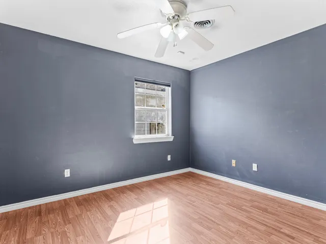 an empty room with a window and ceiling fan
