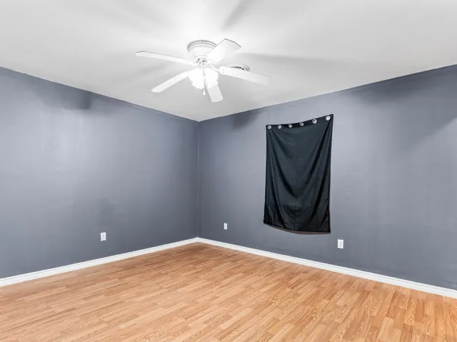 a view of a room with wooden floor and ceiling fan