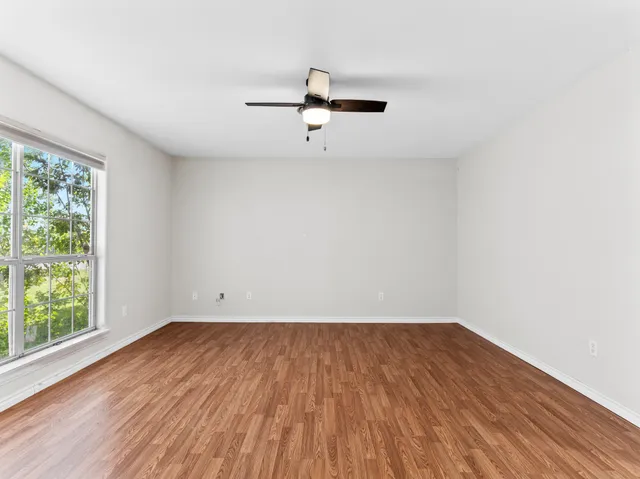 an empty room with wooden floor and windows