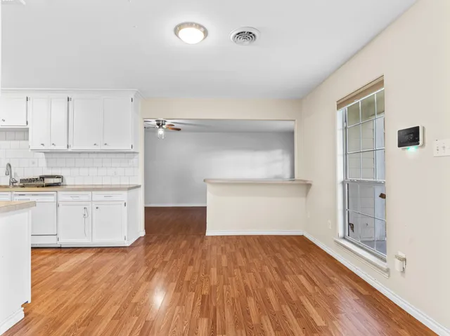 a kitchen with wooden floors and white cabinets
