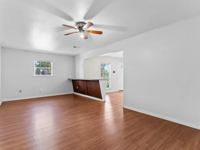 a view of an empty room with window and wooden floor