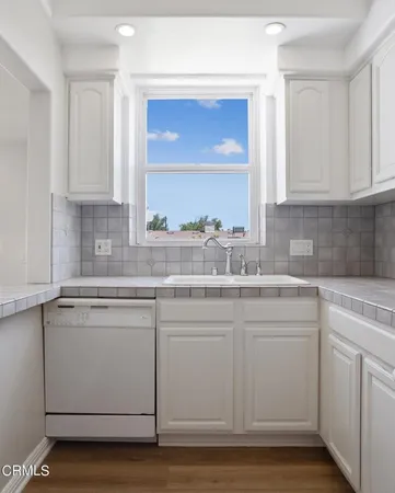 a kitchen with white cabinets and sink