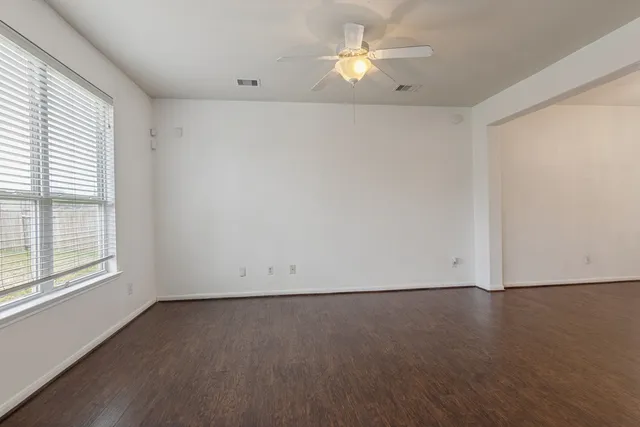 an empty room with a window and a ceiling fan