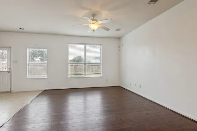 an empty room with wooden floor and windows