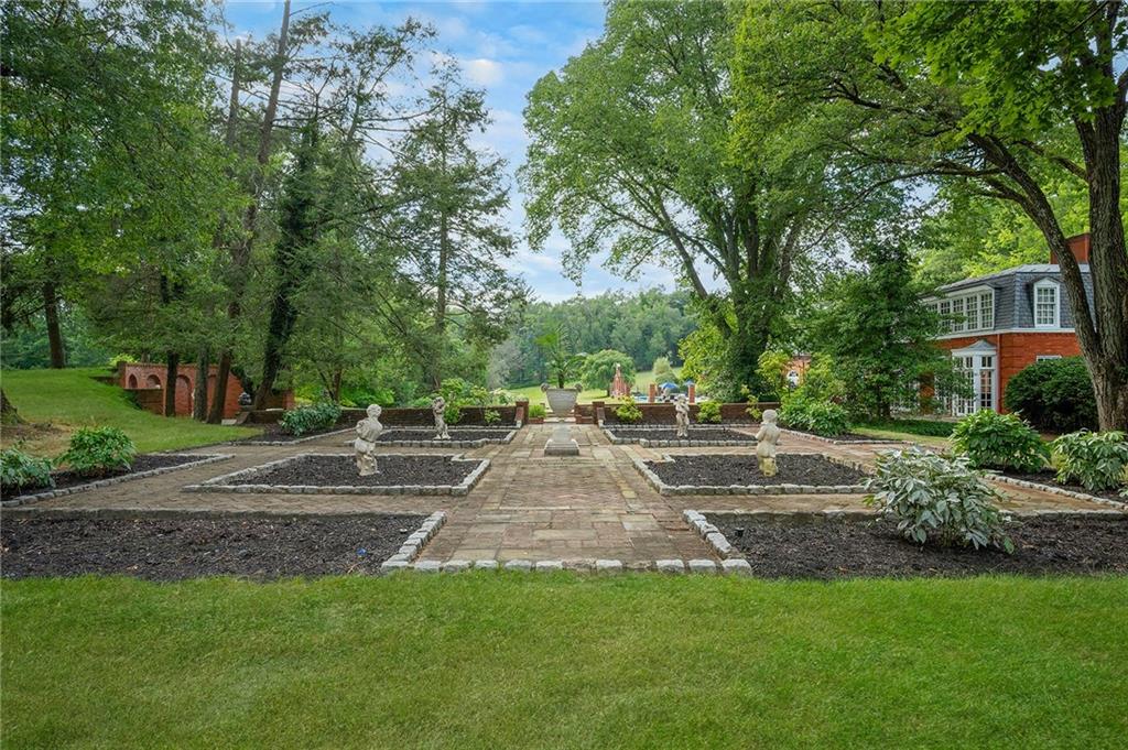 898 Persimmon Road Sewickley, PA 15143 - Photo 49 of 50 The Four Seasons Garden features a symmetrical brick walkway flanked by four distinct planting beds, each anchored by a classical cherub statue. Surrounded by lush trees and manicured greenery, this elegant space offers a timeless setting that transitions beautifully through all seasons.
