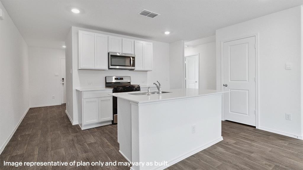 3522 Spring Time Street Forney, TX 75126 - Photo 2 of 27 Kitchen island with an undermount sink, white cabinetry, stainless steel microwave, stainless steel range, and wood-finish flooring