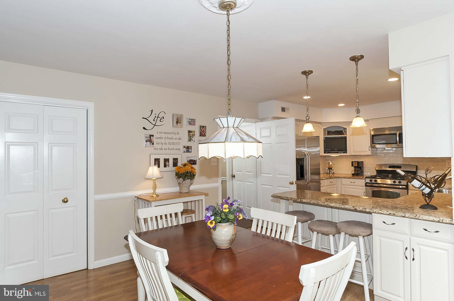 14903 Peach Orchard Road Silver Spring, MD 20905 - Photo 10 of 30 a kitchen with a refrigerator a sink dishwasher a dining table and chairs with wooden floor