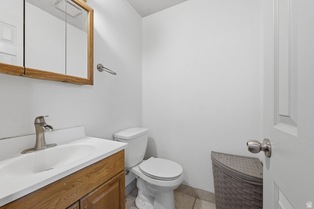 1700 Hickory Lane Provo, UT 84604 - Photo 20 of 20 Bathroom featuring a wood-finish vanity with an integrated sink, a satin nickel faucet, a wood-framed medicine cabinet, and ceramic tile flooring