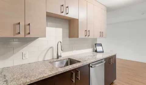 a kitchen with granite countertop a sink and a white cabinets