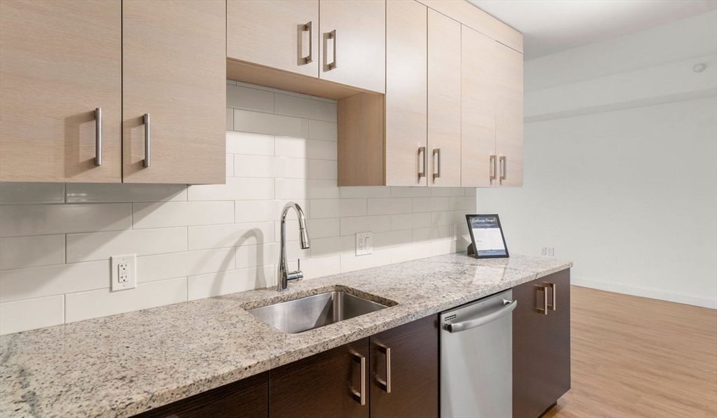 99 Kneeland Street, Unit 611 Boston, MA 02111 - Photo 4 of 15 a kitchen with granite countertop a sink and a white cabinets