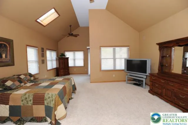 a bedroom with a bed and a flat tv screen on dresser