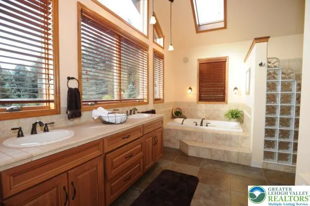a bathroom with a double vanity sink large mirror and a bathtub