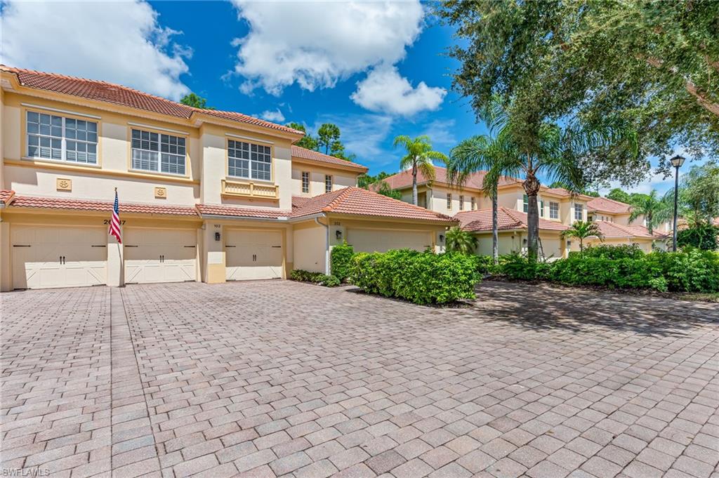 26437 Lucky Stone Road, Unit 102 Bonita Springs, FL 34135 - Photo 2 of 25 a front view of a house with a yard and a garage