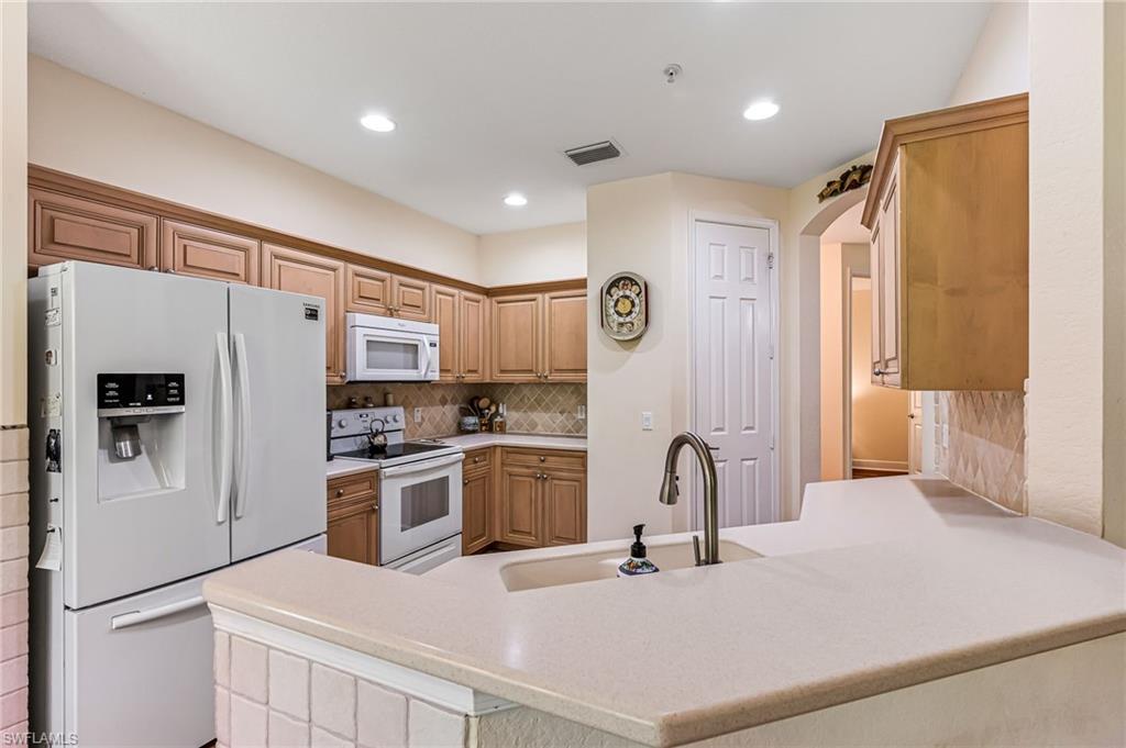26437 Lucky Stone Road, Unit 102 Bonita Springs, FL 34135 - Photo 8 of 25 a kitchen with stainless steel appliances a refrigerator sink and cabinets