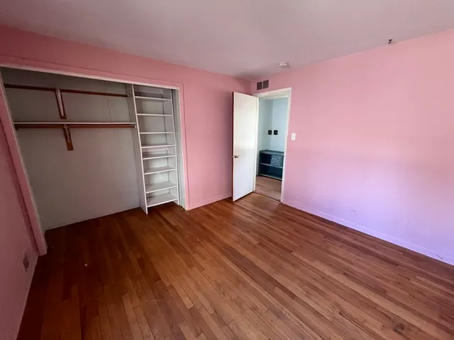 a view of empty room with wooden floor and closet