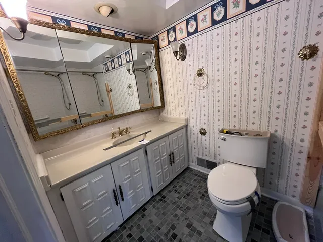 a bathroom with a granite countertop toilet sink and mirror
