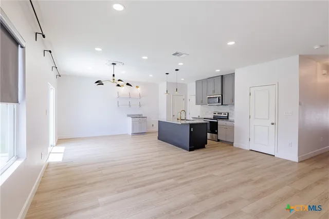 a large white kitchen with a refrigerator and a stove top oven