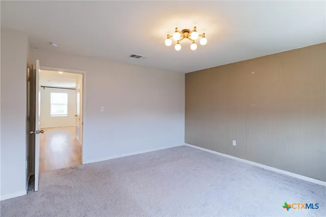 a view of an empty room with a chandelier fan