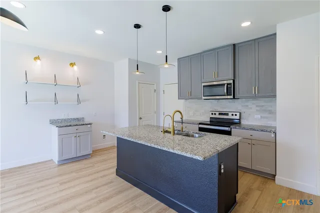 a kitchen with kitchen island granite countertop a sink cabinets and wooden floor