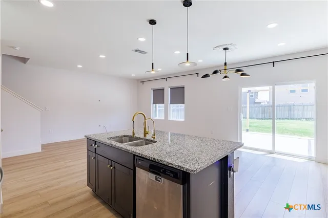 a kitchen with granite countertop kitchen island stainless steel appliances a sink stove and wooden floor