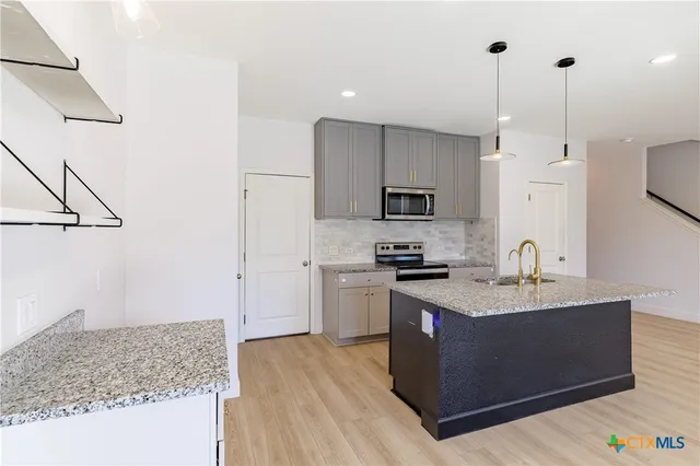 a kitchen with stainless steel appliances granite countertop a sink stove and refrigerator