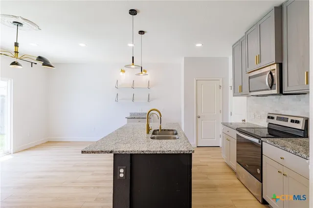 a kitchen with granite countertop cabinets a sink a stove and refrigerator