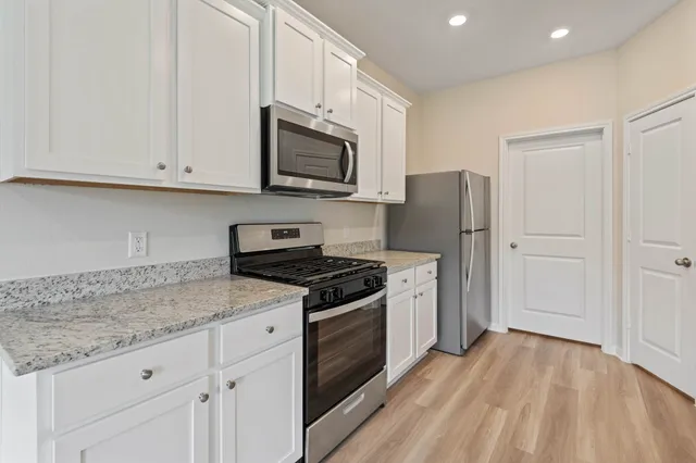a kitchen with stainless steel appliances granite countertop white cabinets granite counter tops and a hard wood floors