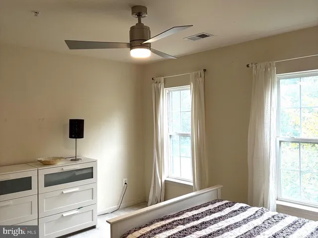 a view of a bedroom with a window and a ceiling fan