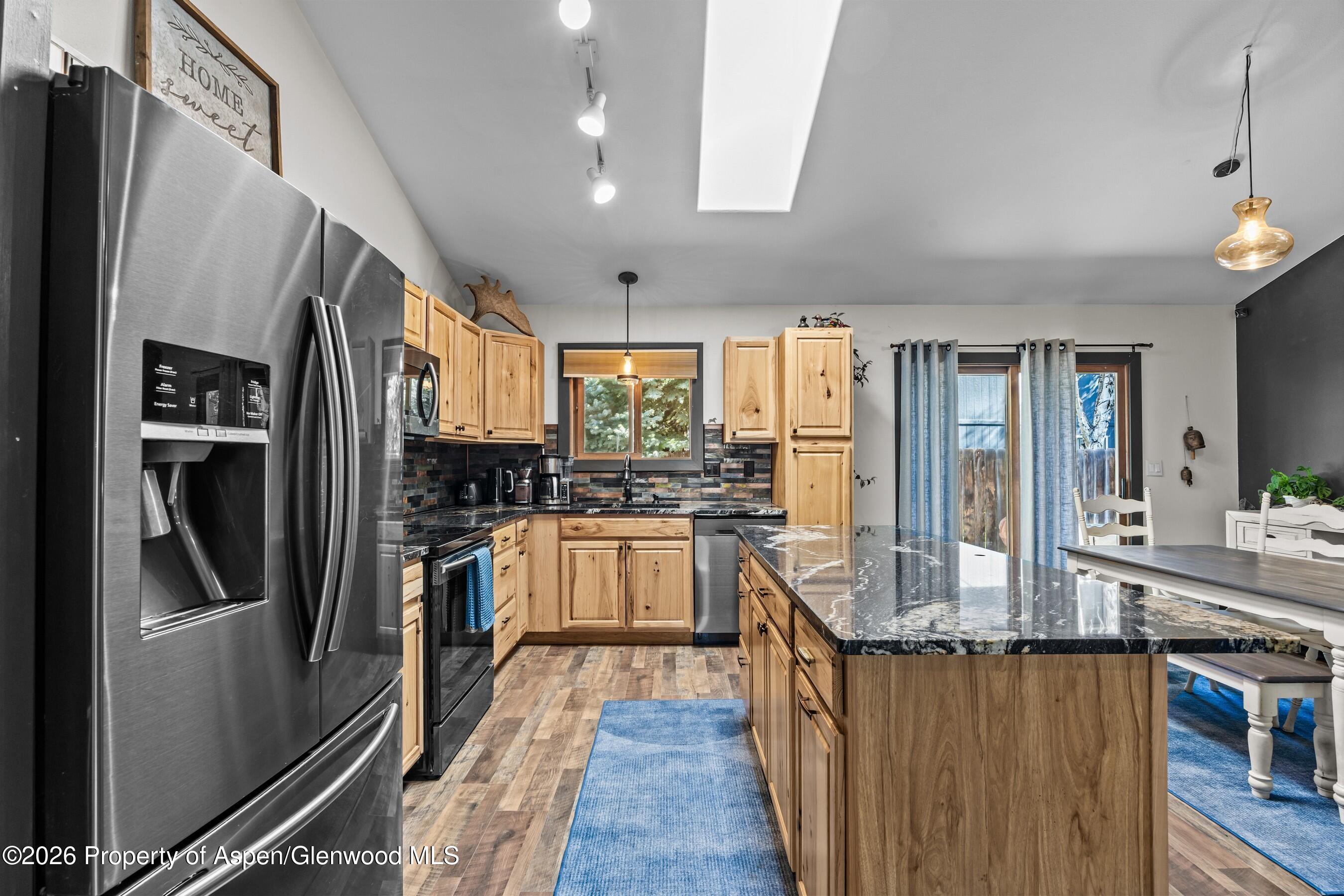 212 Safflower Court New Castle, CO 81647 - Photo 9 of 27 a kitchen with stainless steel appliances granite countertop a refrigerator a stove and a sink with wooden floor