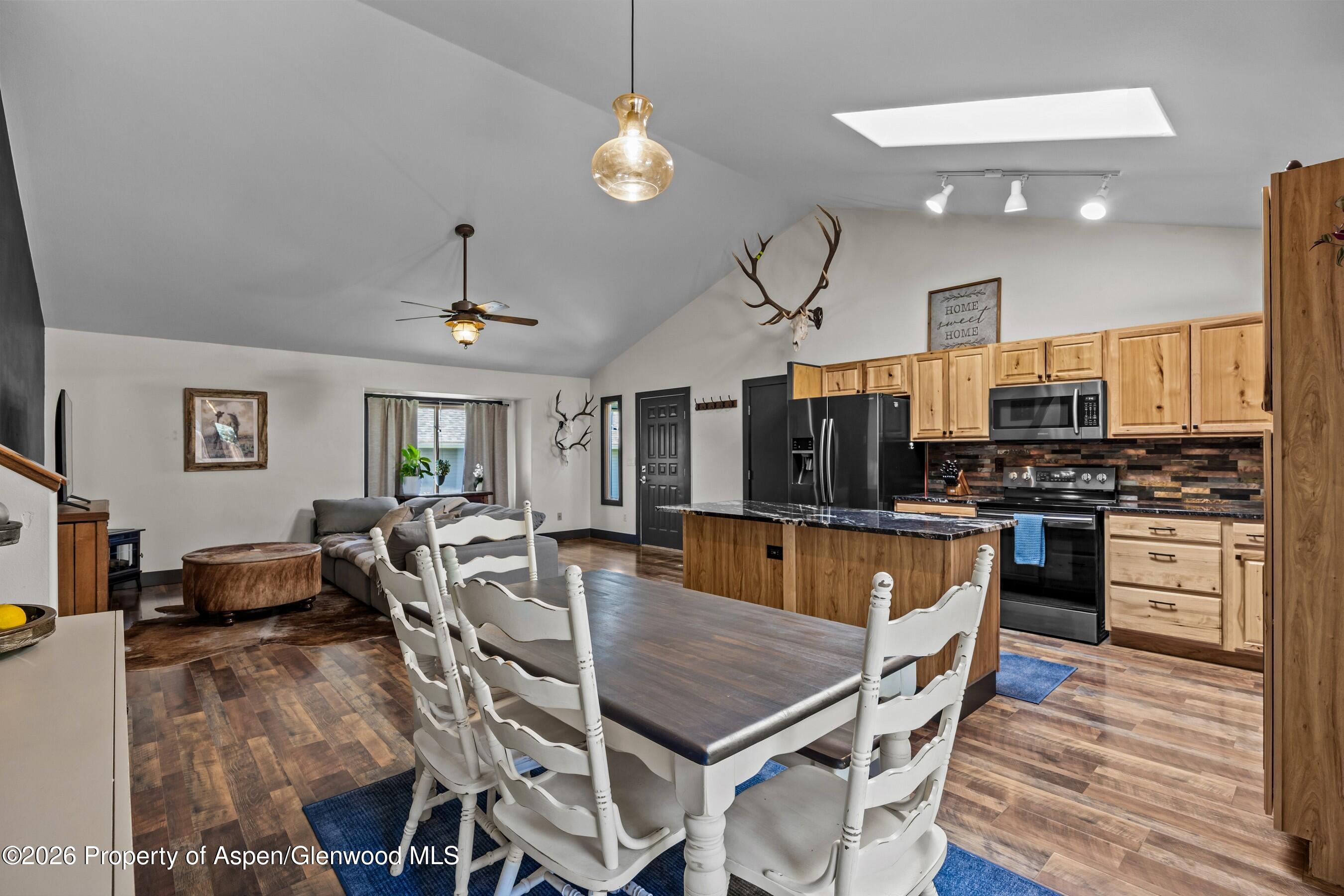 212 Safflower Court New Castle, CO 81647 - Photo 10 of 27 a dining room with stainless steel appliances kitchen island granite countertop a stove a refrigerator a oven a dining table and chairs with wooden floor