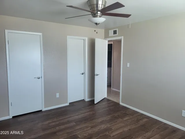 an empty room with wooden floor a ceiling fan and staircase