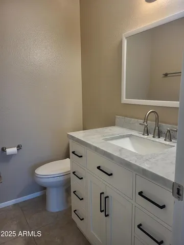 a bathroom with a granite countertop toilet and a sink