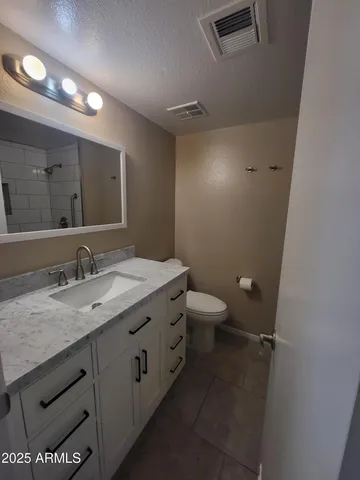 a bathroom with a granite countertop sink a toilet and a mirror