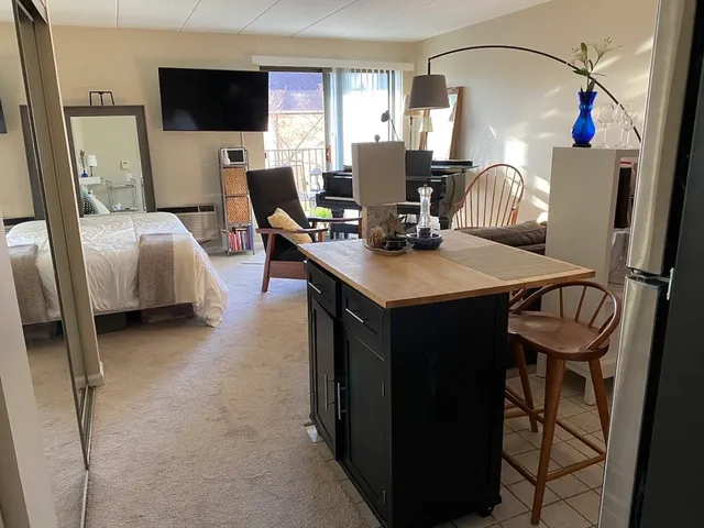 a living room with furniture a flat screen tv and a refrigerator