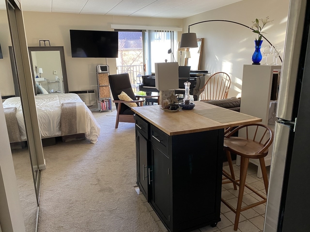 60 Pleasant Street, Unit 211 Arlington, MA 02476 - Photo 3 of 12 a living room with furniture a flat screen tv and a refrigerator