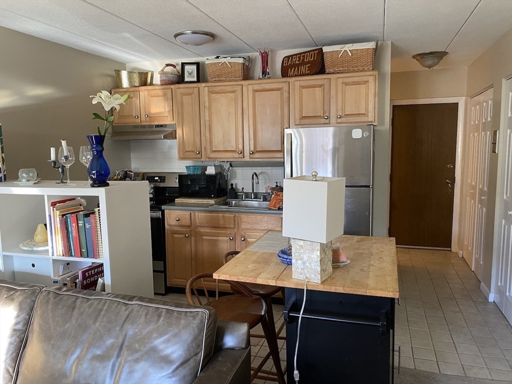 60 Pleasant Street, Unit 211 Arlington, MA 02476 - Photo 4 of 12 a kitchen with refrigerator and chairs