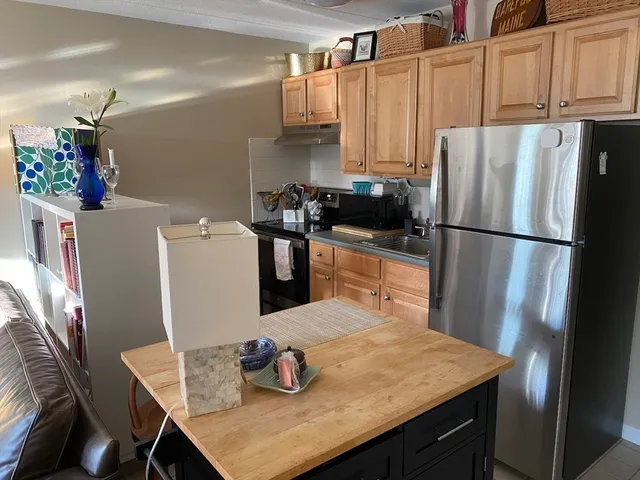 a kitchen with stainless steel appliances a refrigerator a sink a stove a dining table and chairs