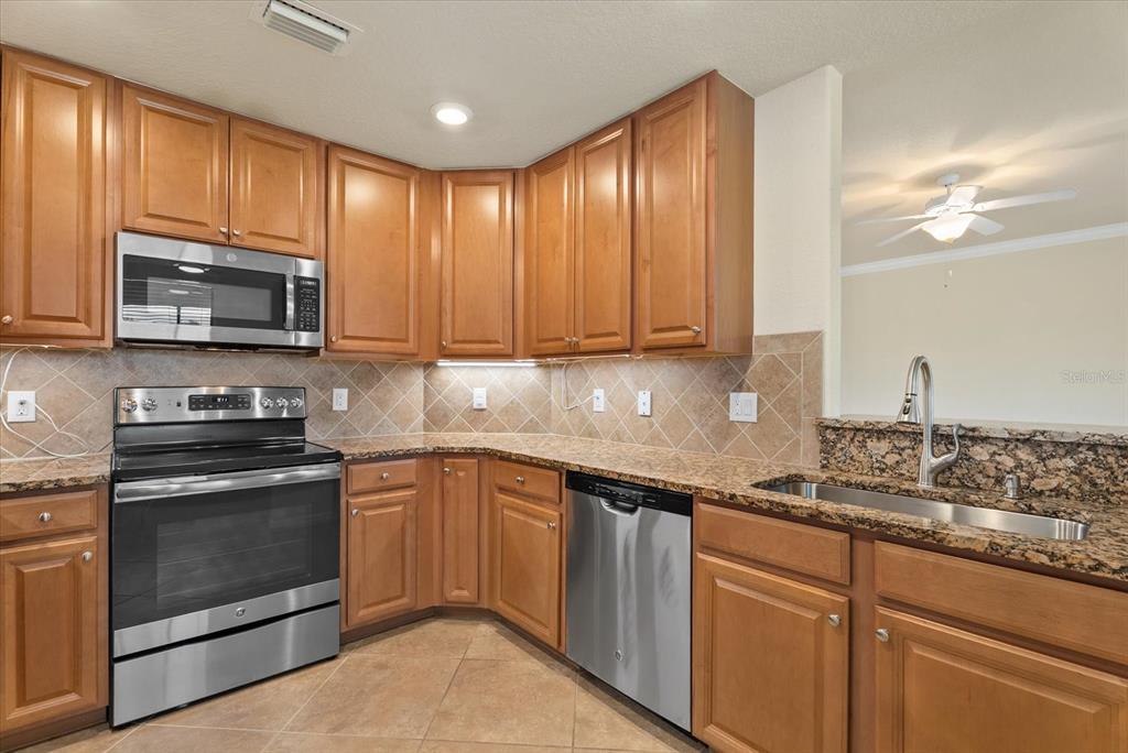 20080 Ragazza Circle, Unit 102 Venice, FL 34293 - Photo 20 of 49 a kitchen with granite countertop wooden cabinets and stainless steel appliances