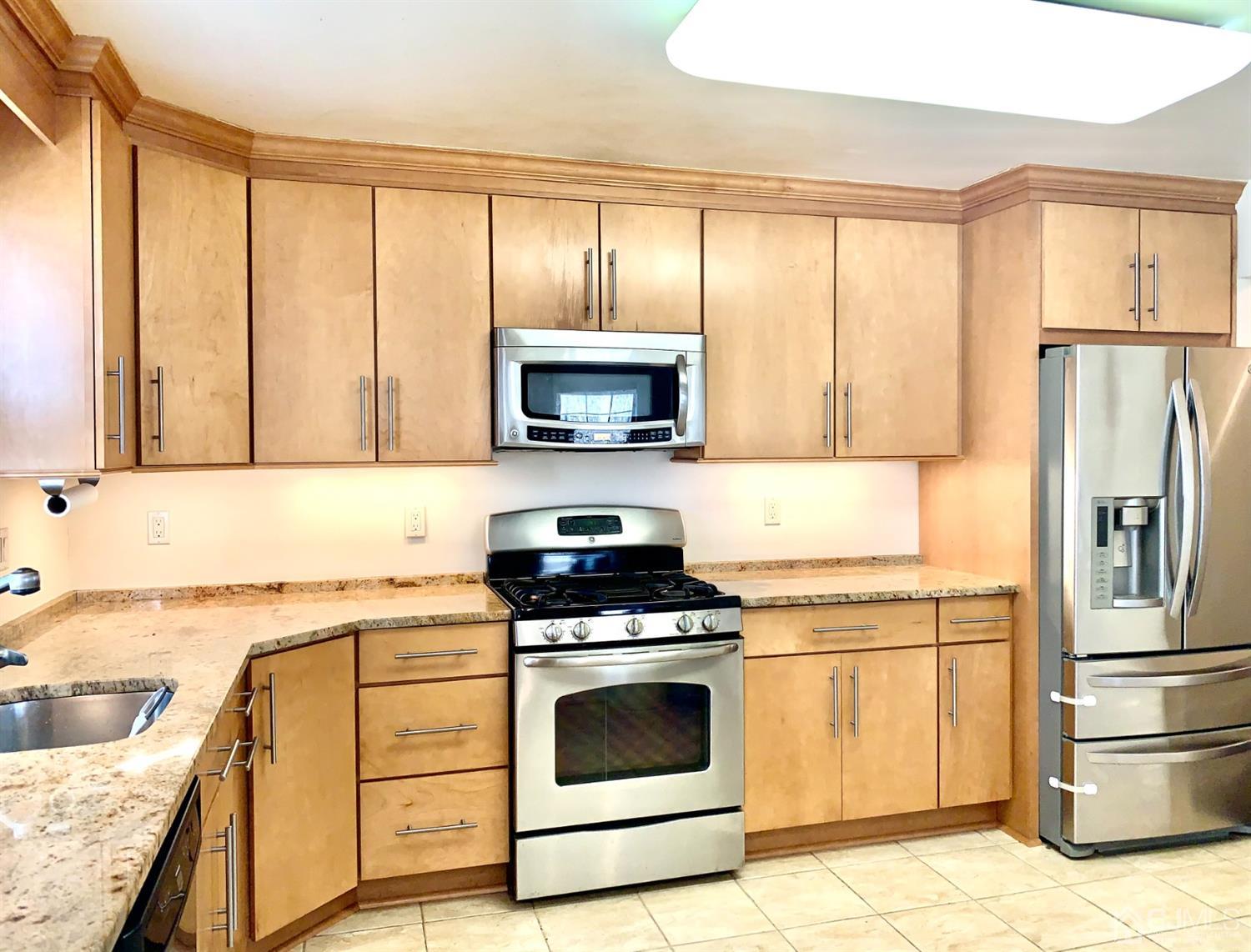 1001 Timber Oaks Road, Unit 1001 Edison, NJ 08820 - Photo 17 of 25 a kitchen with a stove a sink and a refrigerator