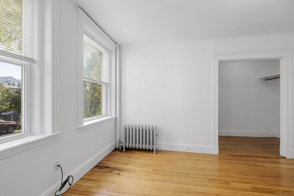 170 Maple Street, Unit 110 Malden, MA 02148 - Photo 14 of 23 an empty room with wooden floor and windows