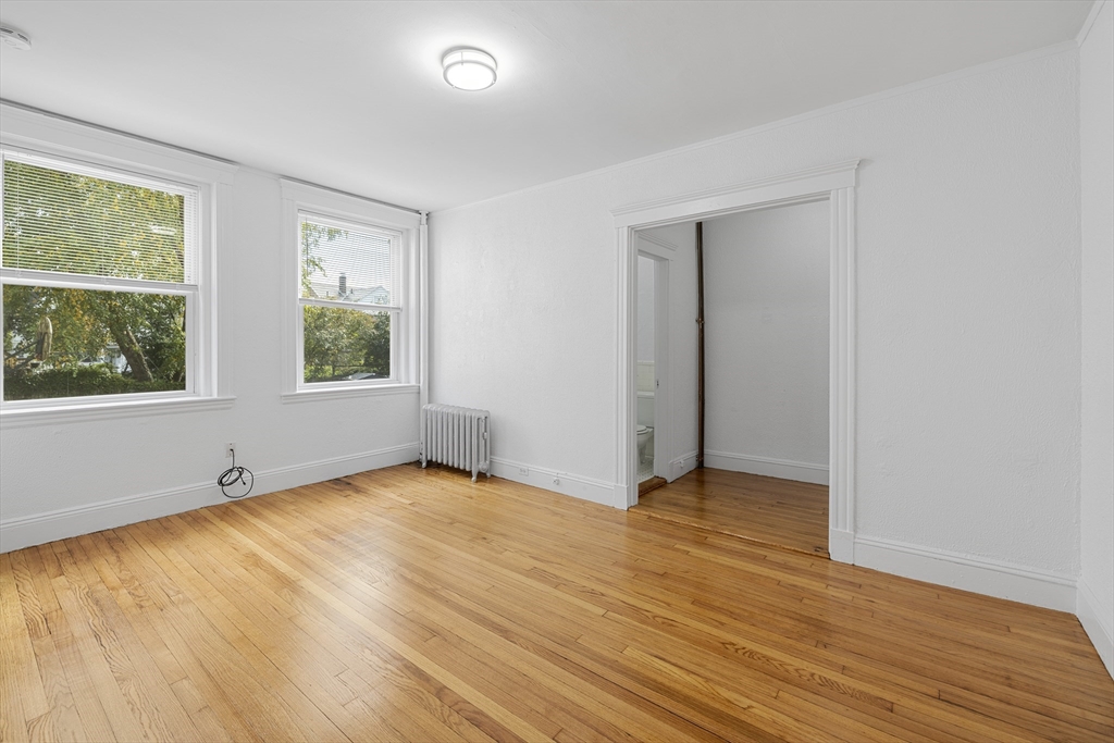 170 Maple Street, Unit 110 Malden, MA 02148 - Photo 2 of 23 an empty room with wooden floor and windows
